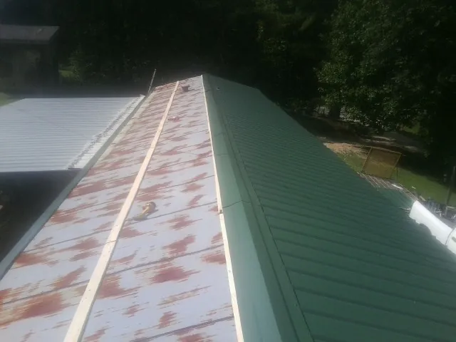 Old rusted panels beside newly installed green metal roofing — Wind Damage Roof Repair by Roofing Brothers in Mill Creek