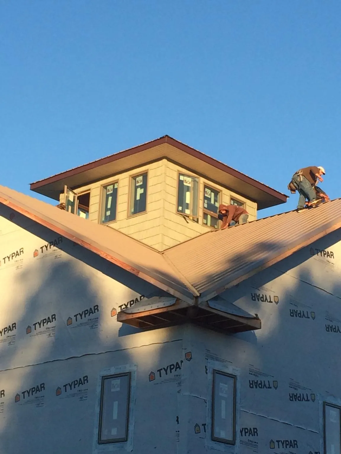 Roofers working around a rooftop cupola on a new metal roof at sunset — Roof Waterproofing in Mill Creek by Roofing Brothers